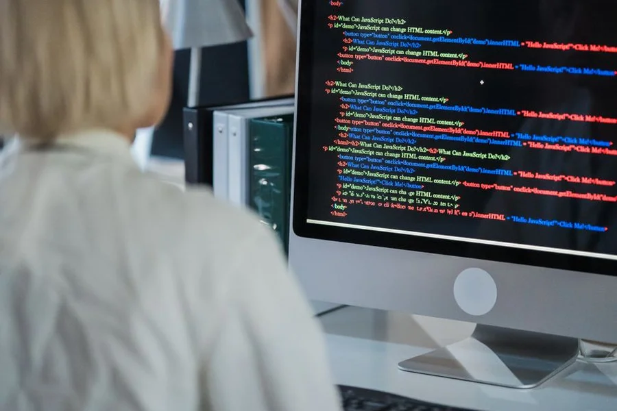 Security analyst reviewing computer system code and network logs on monitor
